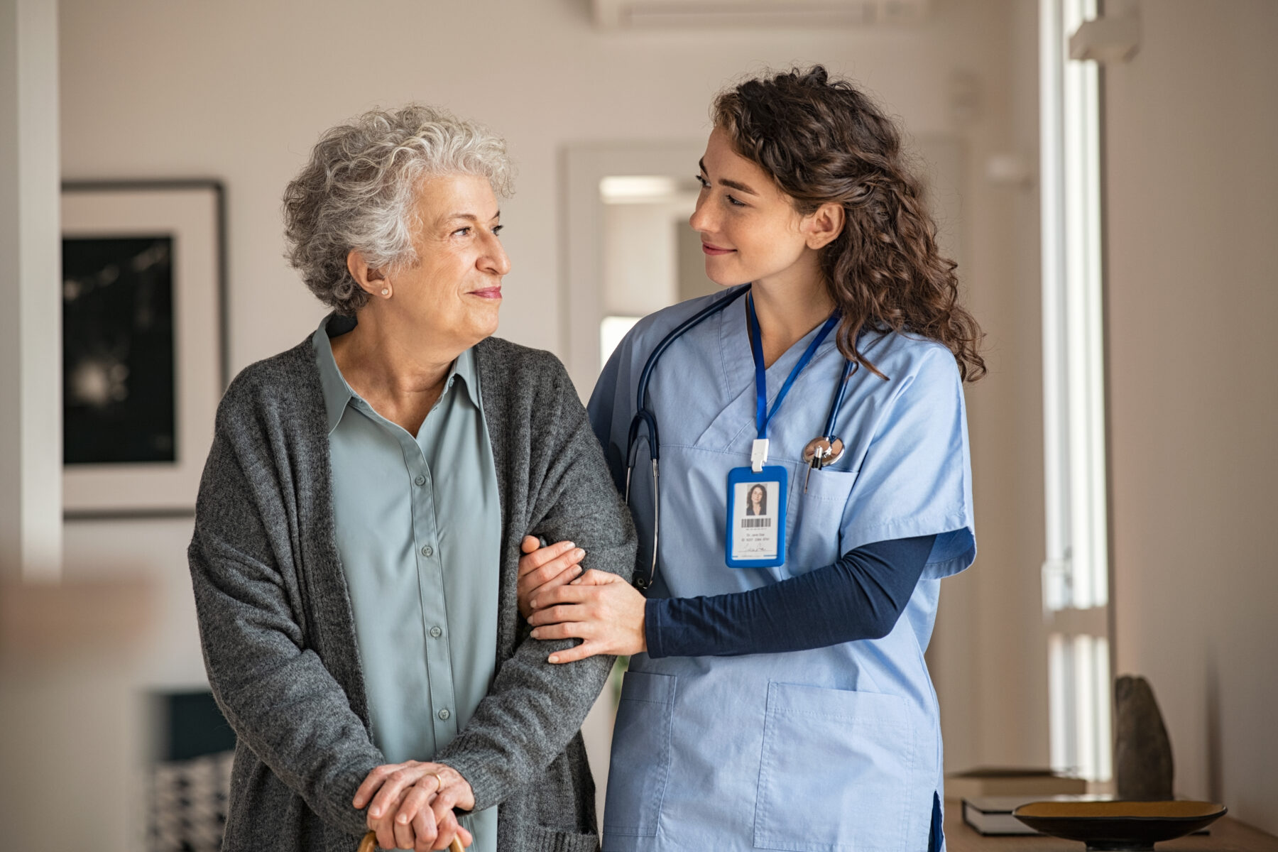 Caregiver helping senior woman walking.